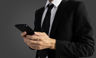 Businessman in black suit standing holding mobile phone to view work data and check work