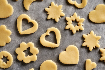 Heart and star shapes made of raw pastry dough on a sheet of baking paper - preparation of Linzer Christmas cookies