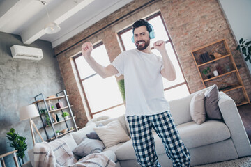 Photo of crazy optimistic man wear pajama dancing music chill living room modern loft interior...
