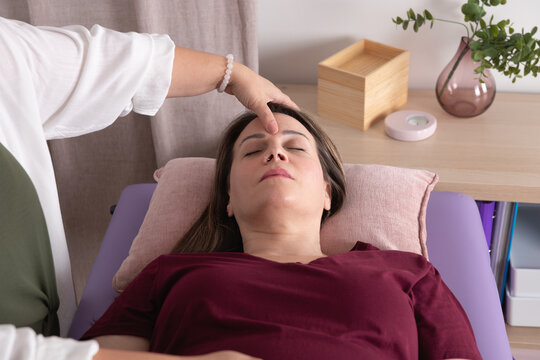 Close-up view from above of a woman receiving acupressure on her face. Concept of therapy, wellness, psychotherapy, kinesiology and acupressure