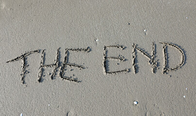 text with the words THE END carved into the sandy beach by the ocean shore