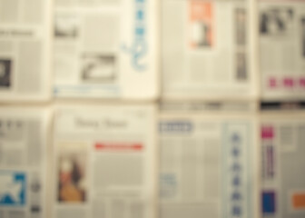 Old news papers create a blurry abstract background with no clear focus.