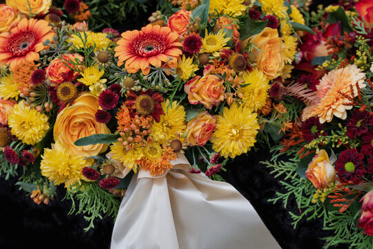 Bunte Blumengebinde am Grab aus verschiedenen Bl&uuml;ten