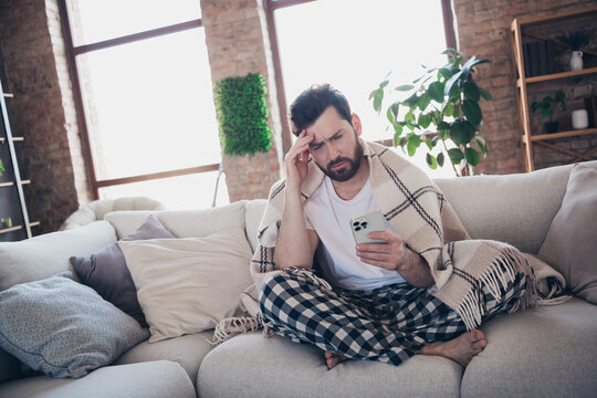 Photo of bearded man wearing pajama wrapped warm plid staying home feeling unwell after party indoors