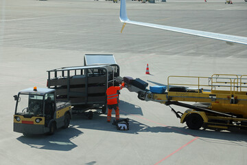 baggage handler wearing high visibility reflective suit unloading bags at the international airport