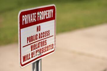 Rectangle image of a red and white PRIVATE PROPERTY, NO PUBLIC ACCESS, VIOLATORS WILL BE PROSECUTED sign  screwed to a metal post, side view with copy space