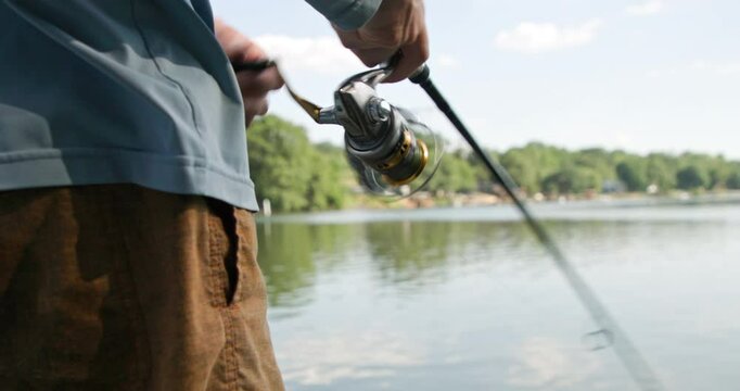 Closeup low shot of a man's hands reeling while fishing on the Catawba River near Charlotte, North Carolina. No audio.