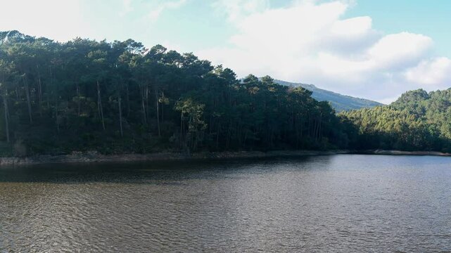 The rio da mula dam reflecting sunlight on a partly cloudy day