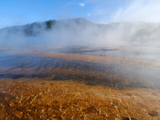 Textures and colors in the Grand Prismatic Springs of Yellowstone National Park with steam rising from the hot boiling waters That flow into the Riverhole river nearby
