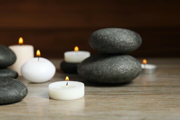 Beautiful composition with burning wax candles, stones on the tablе