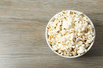 Delicious popcorn in a bowl on a color background