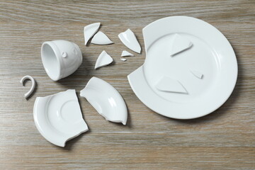 White cup and plate broken on gray background