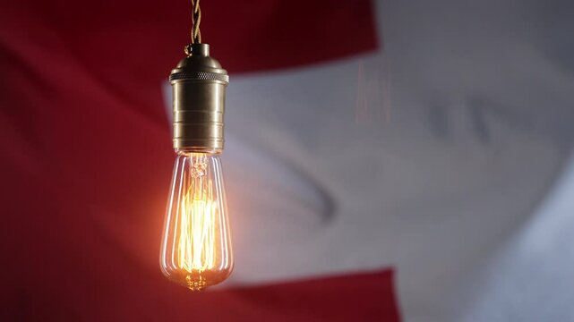 Glowing Edison light bulb on Switzerland flag background. Electricity price, bills, energy crisis, raising tariffs. 