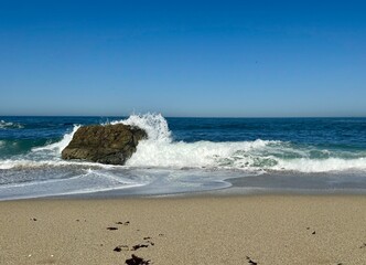 waves on the beach hitting rock.