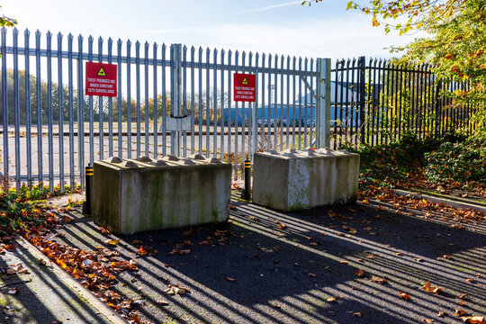 Sunlit industrial metal gate blocked with concrete blocks.
