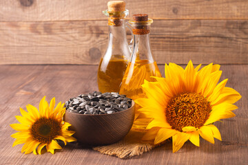 Closeup photo of sunflower oil with seeds on wooden background. Bio and organic product concept.