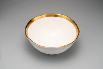  white bowl with a gold rim sitting on a grey surface