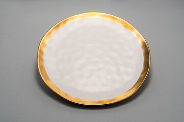  white plate with a gold rim sitting on a grey surface