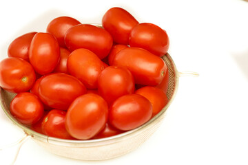 Pile of ripe red delicious tomatoes for cooking on plate on white