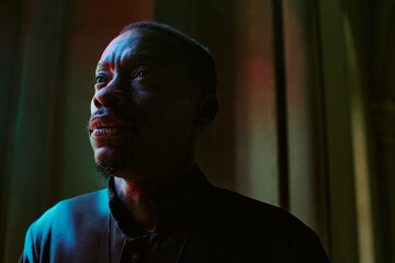 Medium close up of African American priest immersed into own thought while standing in church