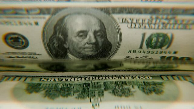 A stack of hundred-dollar bills in a calculating machine, slow motion.  Calculation of the American currency. 4K loop 3D animation