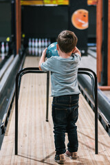 Little boy throwing bowling ball in bowling alley