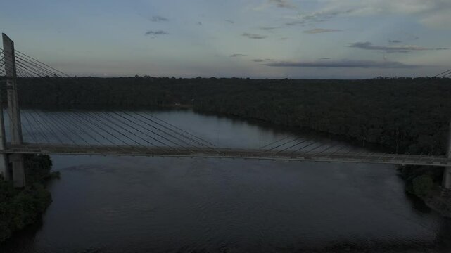 Drone flies over suspension bridge crossing from French Guyana to Brazil in Amap&aacute; in the early evening