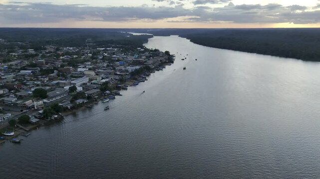 Drone orbits to the right high over the Oiapoque River at sunset facing the town of Oiapoque, Amap&aacute;, Brazil