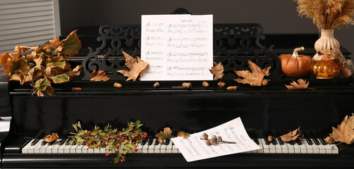 Grand piano with autumn decorations and note sheets in room