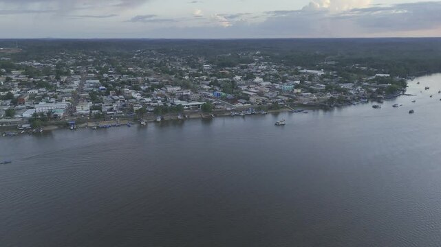 Drone flies to the right over Oiapoque River facing Oiapoque, Amap&aacute;, Brazil at sunset