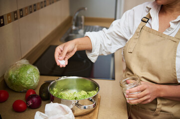 Woman preparing homemade guacamole in kitchen with fresh ingredients
