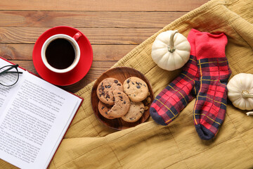 Composition with cup of aromatic coffee, cookies, warm socks and book on wooden background
