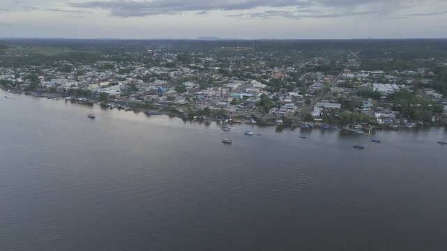 Drone orbits from river to south west side of town facing away from sunset in Oiapoque, Amap&aacute;, Brazil
