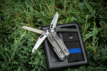 Multitool pocket knife in open case on greenery.