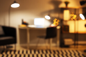 Blurred view of office with workplace and glowing lamps at night