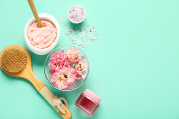 Beautiful flowers with scrub, sea salt and brush on turquoise background. Body massage concept