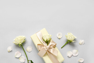 Gift box with roses and petals on white background