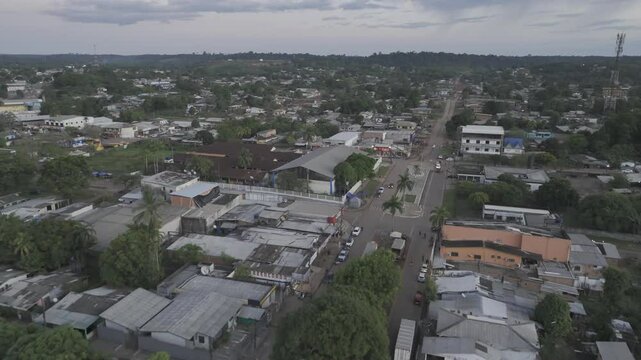 Drone flies over town with streets lined with trees, just after sunset with partially cloudy sky