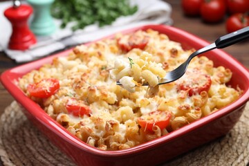 Eating delicious al forno pasta at wooden table, closeup