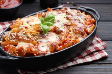 Delicious al forno pasta in baking dish on wooden table, closeup