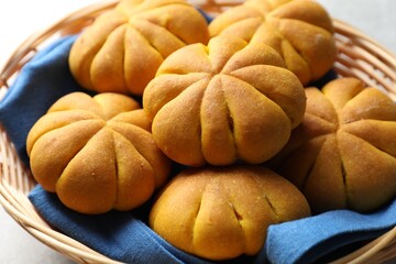 Wicker basket with tasty pumpkin shaped buns on table, closeup