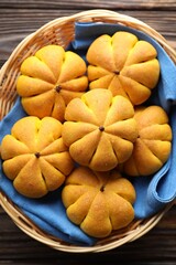 Wicker basket with tasty pumpkin shaped buns on wooden table, top view