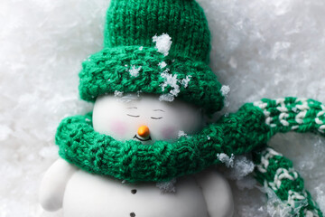 Cute decorative snowman on artificial snow, top view