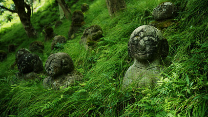 Small Japanese statues on grassy hillside