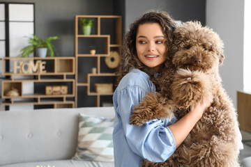 Young woman holding cute poodle at home