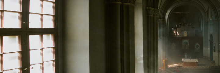 Website banner with high angle of majestic arcades and wall inside church with incense smoke in air