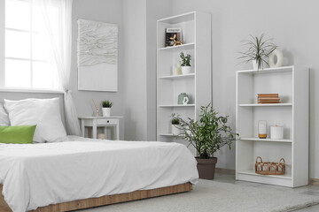 Interior of modern stylish comfortable bedroom with shelving units and different houseplants