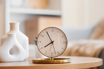 Golden alarm clock and vases on coffee table in room. Closeup
