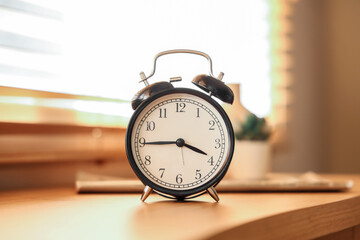 Black alarm clock on table in room. Closeup