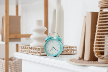 Turquoise alarm clock with decor on shelf in room. Closeup
